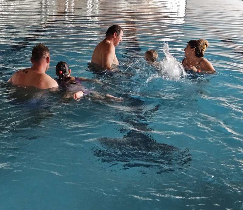 Parent and child splashing feet on the pool edge, both smiling.